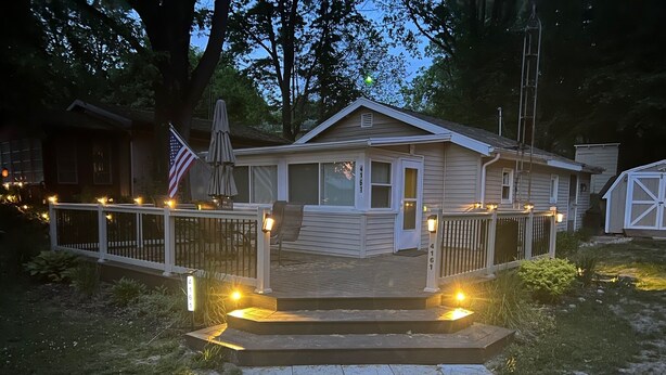 Une maison d’habitation avec une terrasse à l’avant, une boîte aux lettres et un drapeau américain.