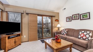 A living room with a television, wooden cabinet, sofa, and a coffee table. - Cozy 2 Bed Townhome with Fireplace + Noon Check In (Galena)