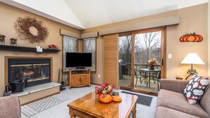 A cozy living room with a fireplace, a television, and a comfortable seating area. - Cozy 2 Bed Townhome with Fireplace + Noon Check In (Galena)