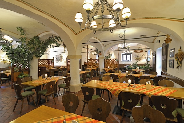 A restaurant with multiple tables, chairs, and a chandelier.