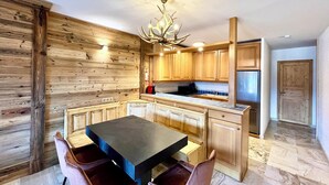 Una cucina moderna con mobili in legno, un tavolo da pranzo nero e un lampadario originale.
