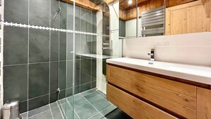 A modern bathroom with a glass shower enclosure, wooden cabinetry, and a white countertop. - The Balcony of the Giant in Combloux (Combloux)