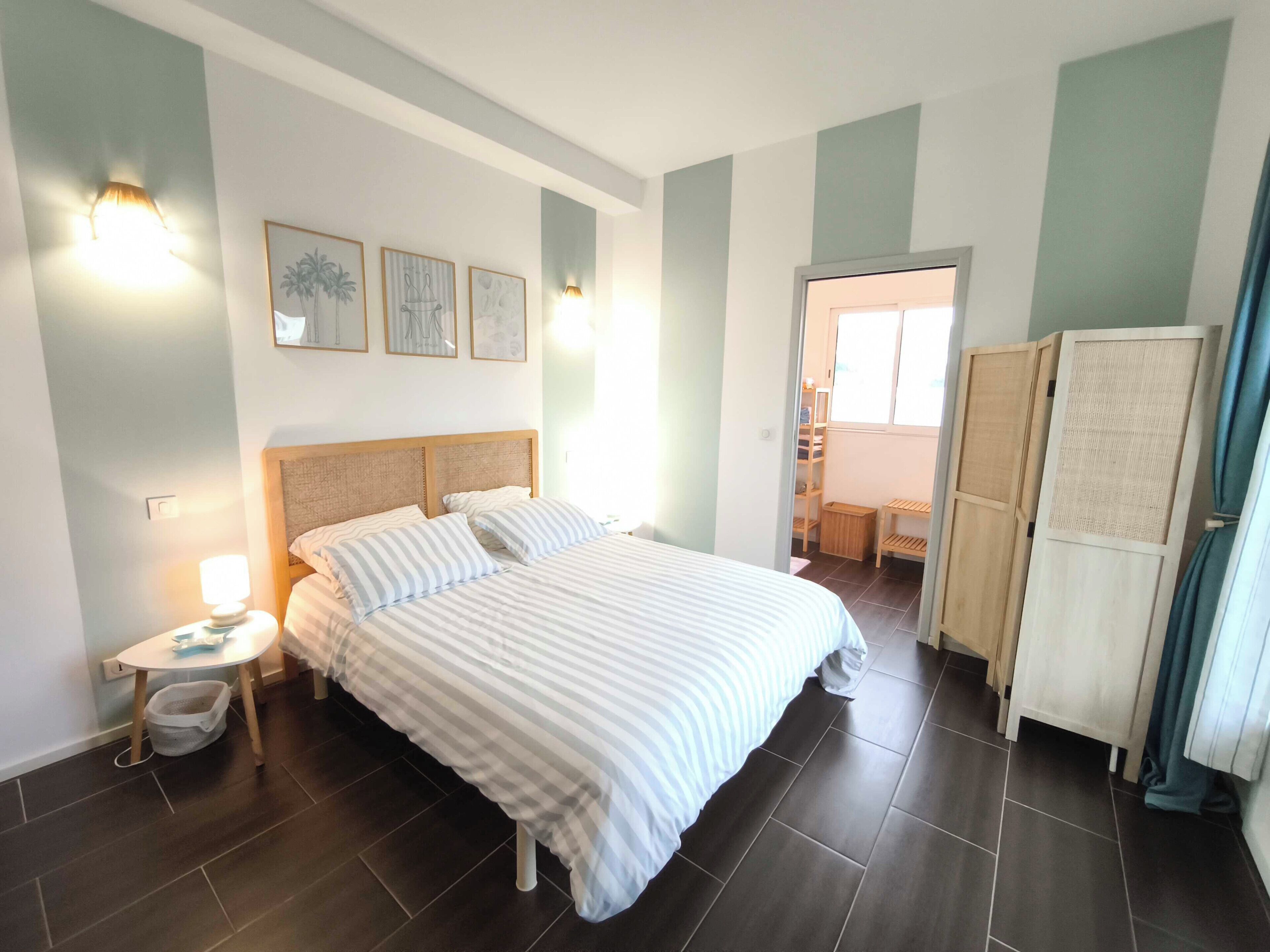 Une chambre à coucher avec un grand lit, des tables de chevet et une armoire.
