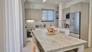 Una cocina moderna con encimera de mármol, electrodomésticos integrados y una ventana con persianas.
