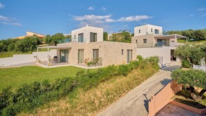 Una casa moderna con fachada de piedra, camino de entrada pavimentado y césped cuidado.