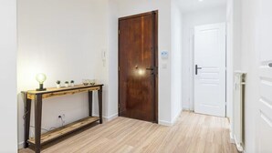 Un pasillo con una puerta de madera, una puerta blanca y una pequeña mesa con una lámpara y plantas.