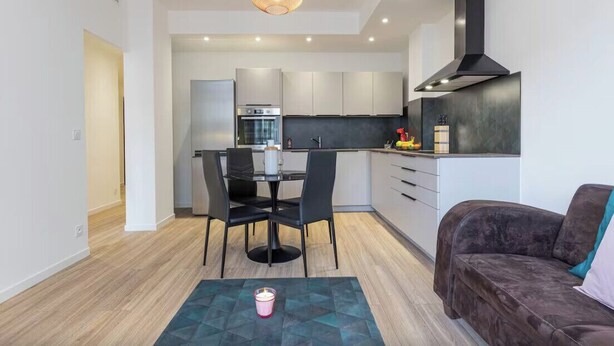 Una cocina moderna con comedor, sofá e iluminación colgante.