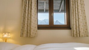 A bedroom with a bed, a window with curtains, and a lamp. - Bright apartment with views of Mont Blanc (Chamonix-Mont-Blanc)
