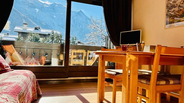 A room with a bed, a wooden desk, and a view of mountains. - Bright apartment with views of Mont Blanc (Chamonix-Mont-Blanc)