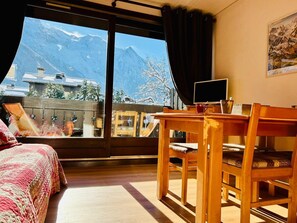 Ein Zimmer mit einem Bett, einem Holztisch und Blick auf Berge.