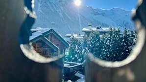 A mountain lodge with a wooden exterior, a snow-covered deck, and a view of snow-covered mountains. - Bright apartment with views of Mont Blanc (Chamonix-Mont-Blanc)