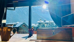 A room with a large window offering a view of snow-covered mountains and buildings. - Bright apartment with views of Mont Blanc (Chamonix-Mont-Blanc)