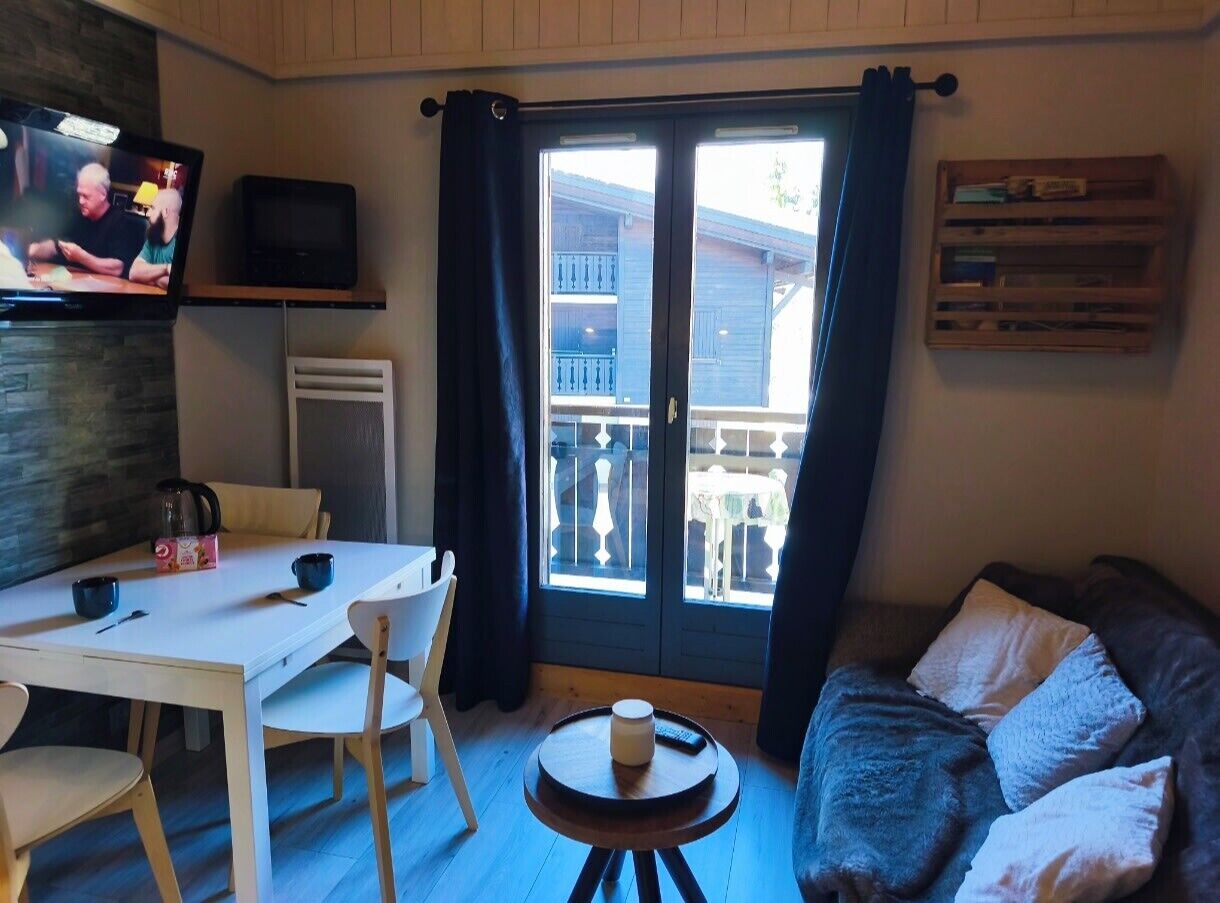A cozy living room with a dining table, a sofa, and a TV.