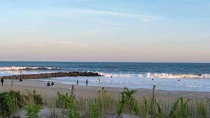 Une plage avec des vagues, des gens et un ciel dégagé.