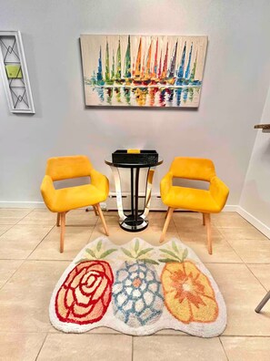 A room with two yellow chairs, a small table, and a colorful rug. - Charming Coastal Retreat 1BR (Rockaway Beach)