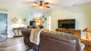 A living room with a brown leather sofa, a television, and a ceiling fan. - Charming Ranch -Bunk North Getaway (Palm City)