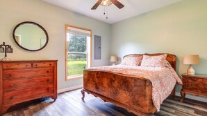 A bedroom with a wooden bed, a dresser, a mirror, and a window with a view of greenery. - Charming Ranch -Bunk North Getaway (Palm City)