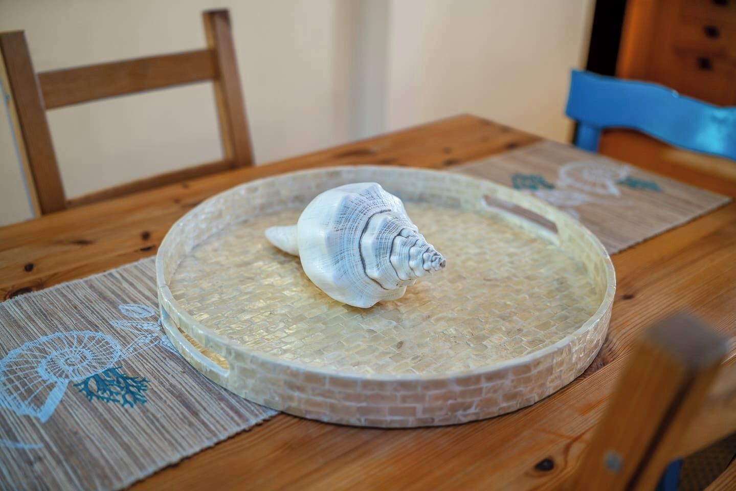 Een ronde tafel met een tafelblad van gestructureerd glas, een witte schaalvormige voet en een houten stoel.