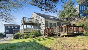 A two-story house with a deck, a garage, and a well-maintained lawn. - Boho Beach House (Tillamook)