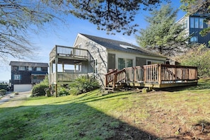 A two-story house with a deck, a garage, and a well-maintained lawn. - Boho Beach House (Tillamook)