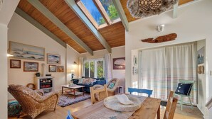 A cozy living room with a wooden ceiling, a dining table, and blue chairs. - Boho Beach House (Tillamook)