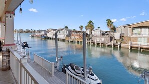 A marina with docked boats, a wooden deck, and waterfront houses. - Stylish Canal-Front Home with Private Dock (Port Isabel)
