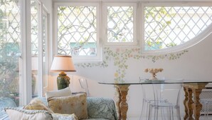 A cozy living room with a sofa, clear chairs, a glass table, and a decorative lamp. - Rental in Rome Rental in Rome Tre Lune Penthouse (Rome)