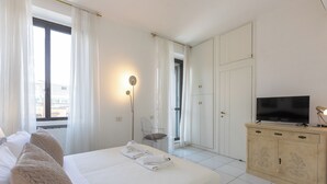 A hotel room with a bed, a TV, a wardrobe, and a chair. - Rental in Rome Rental in Rome Tre Lune Penthouse (Rome)