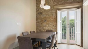Un espace repas avec un mur en pierre, une grande table et des chaises.