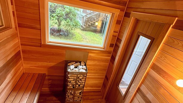 Una sauna de madera con un banco, una ventana y una pequeña mesa con objetos.
