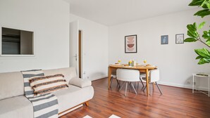 A modern living room with a sofa, dining table, and chairs. - Chic 1BR Steps from Opéra Garnier (Paris)