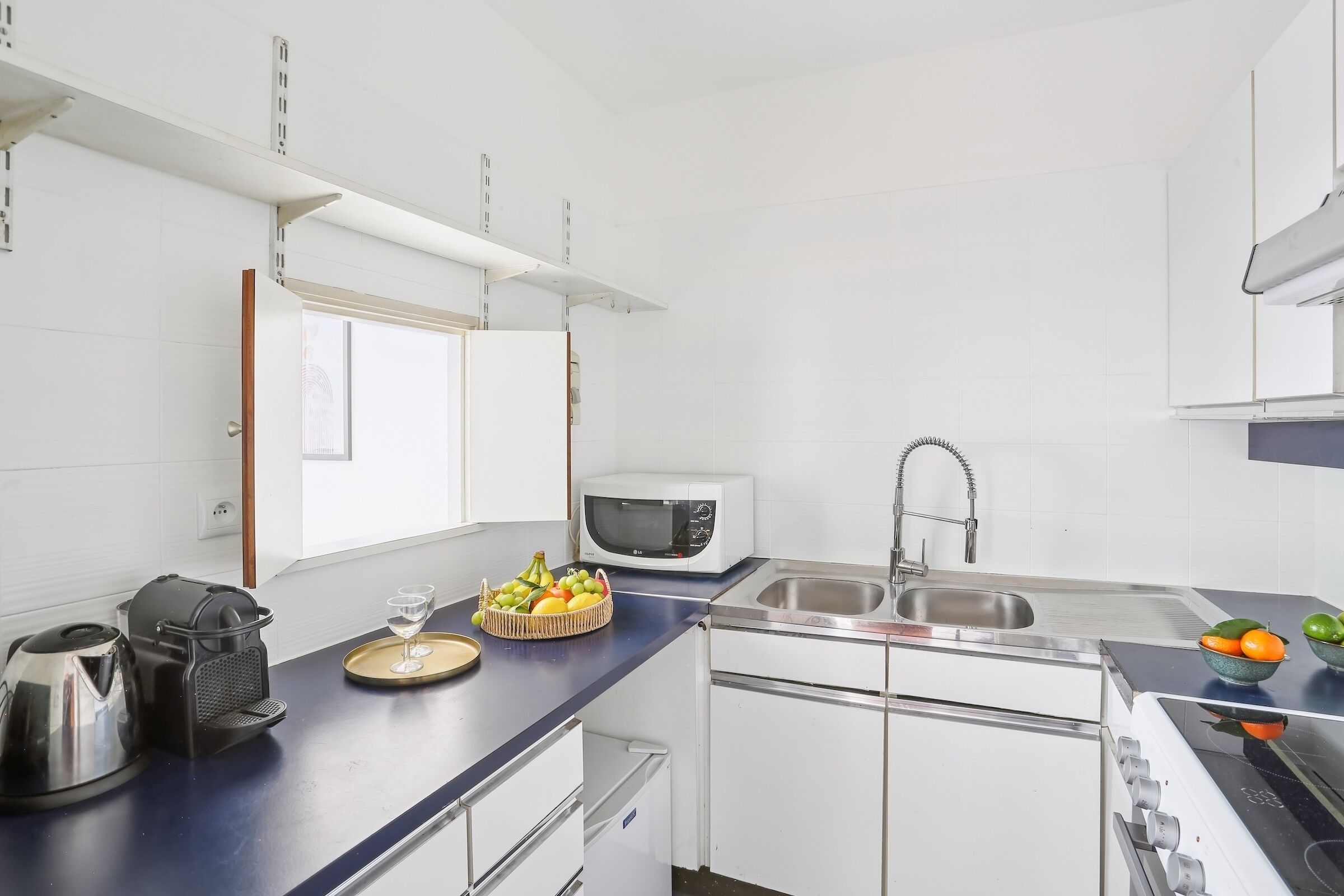 A compact kitchen with white cabinets, a microwave, a sink, and a stove.