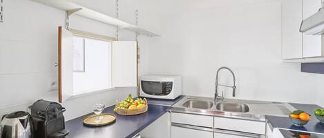 A compact kitchen with white cabinets, a microwave, a sink, and a stove.