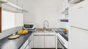 A compact kitchen with white cabinets, a microwave, a sink, and a stove. - Chic 1BR Steps from Opéra Garnier (Paris)