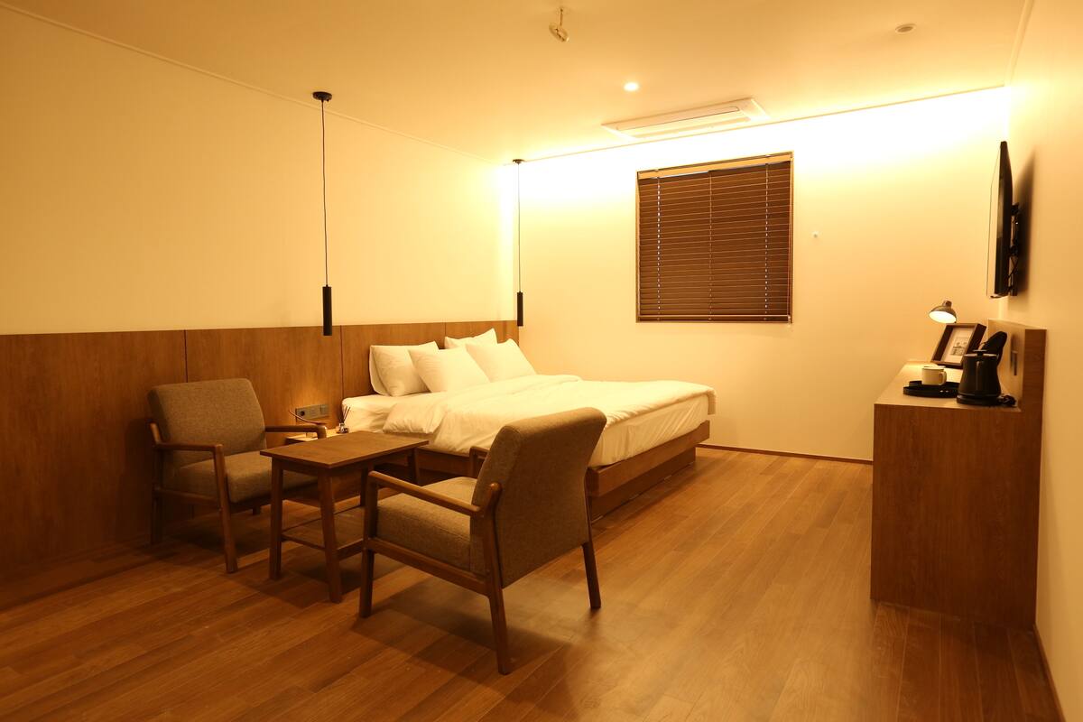 Une chambre d’hôtel comprenant un lit, un bureau, une chaise, une table de chevet, une lampe et un téléviseur.
