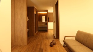 Un interior moderno con piso de madera, un sofá y un baño visible al fondo.
