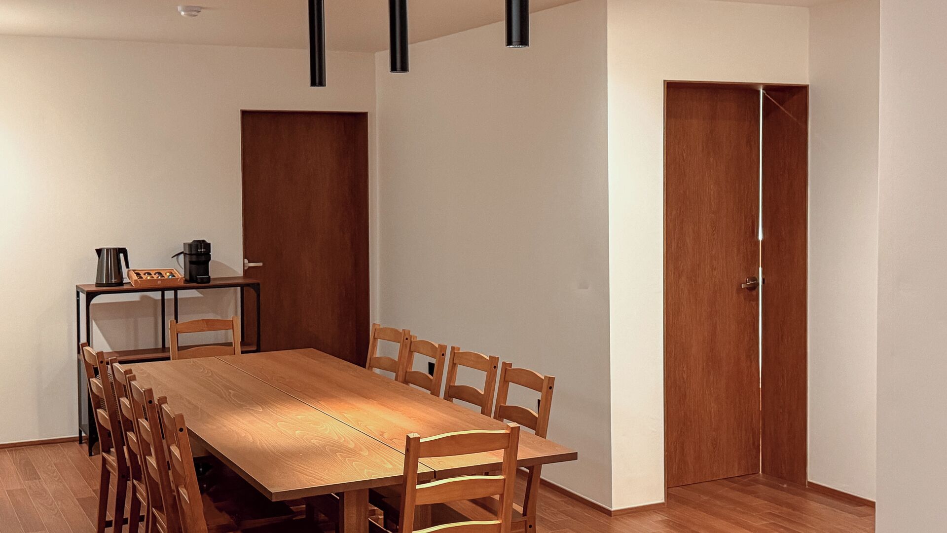 A dining area with a wooden table and chairs, a coffee maker, and a cabinet.