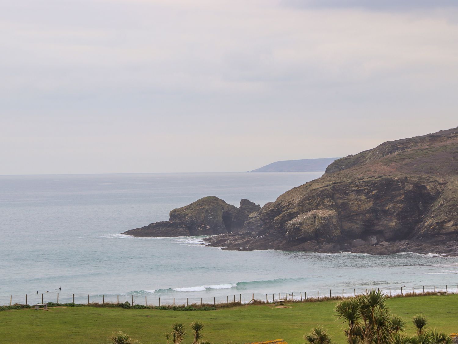 A coastal landscape with rocky cliffs and a grassy foreground.