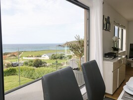 Una cocina moderna con vistas al mar, un comedor con sillas y una pequeña mesa de comedor.