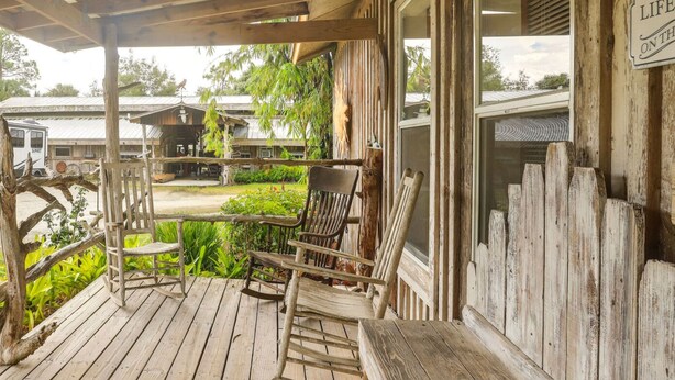 A wooden porch with rocking chairs and a covered area. - Private Lake Access, Enjoy Serenity @ Bunk South (Palm City)