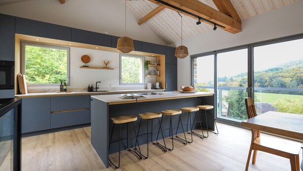 A modern kitchen with a large island, bar stools, and a dining table.
