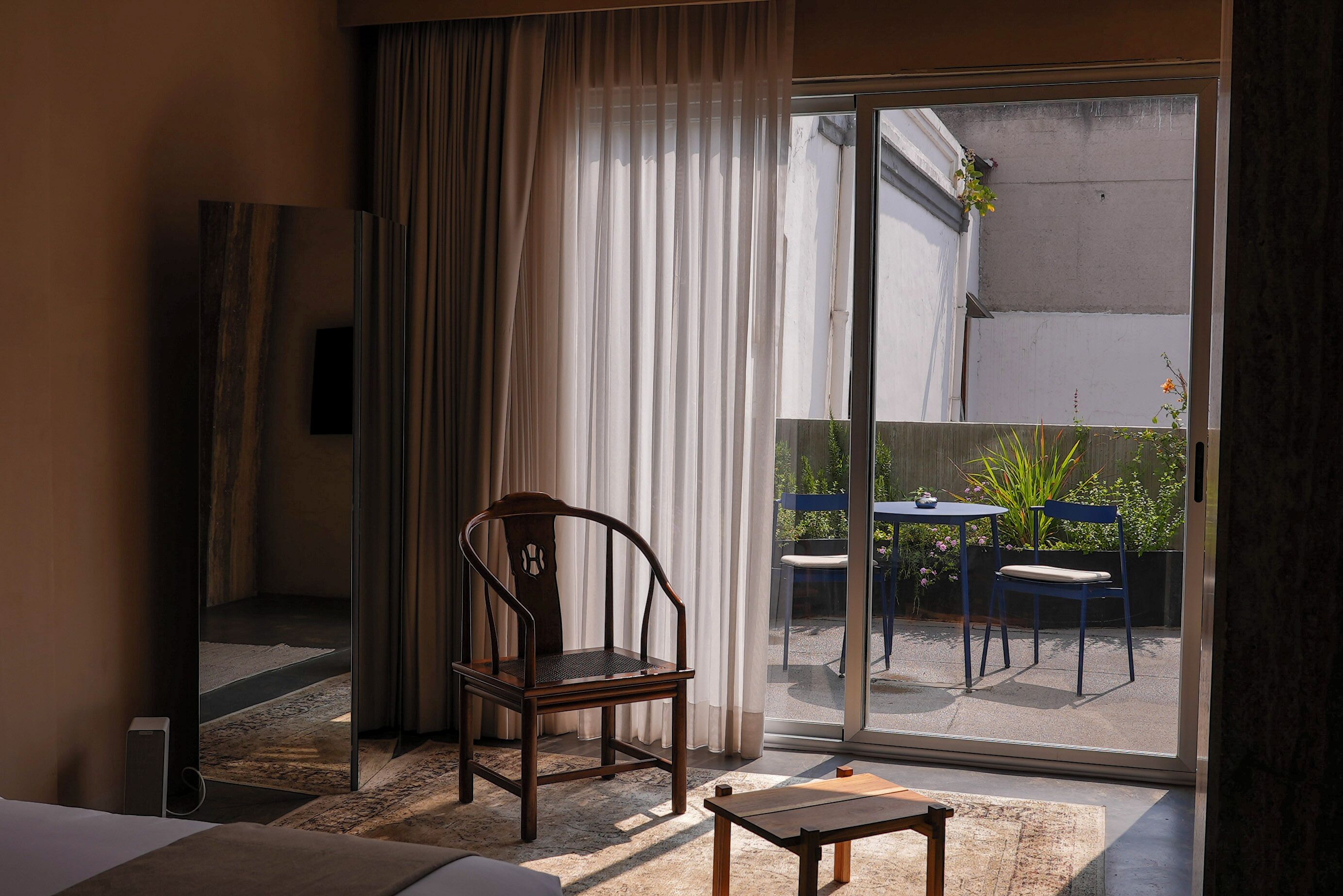 Una habitación de hotel con un gran ventanal corredero que da a un espacio exterior con mobiliario.