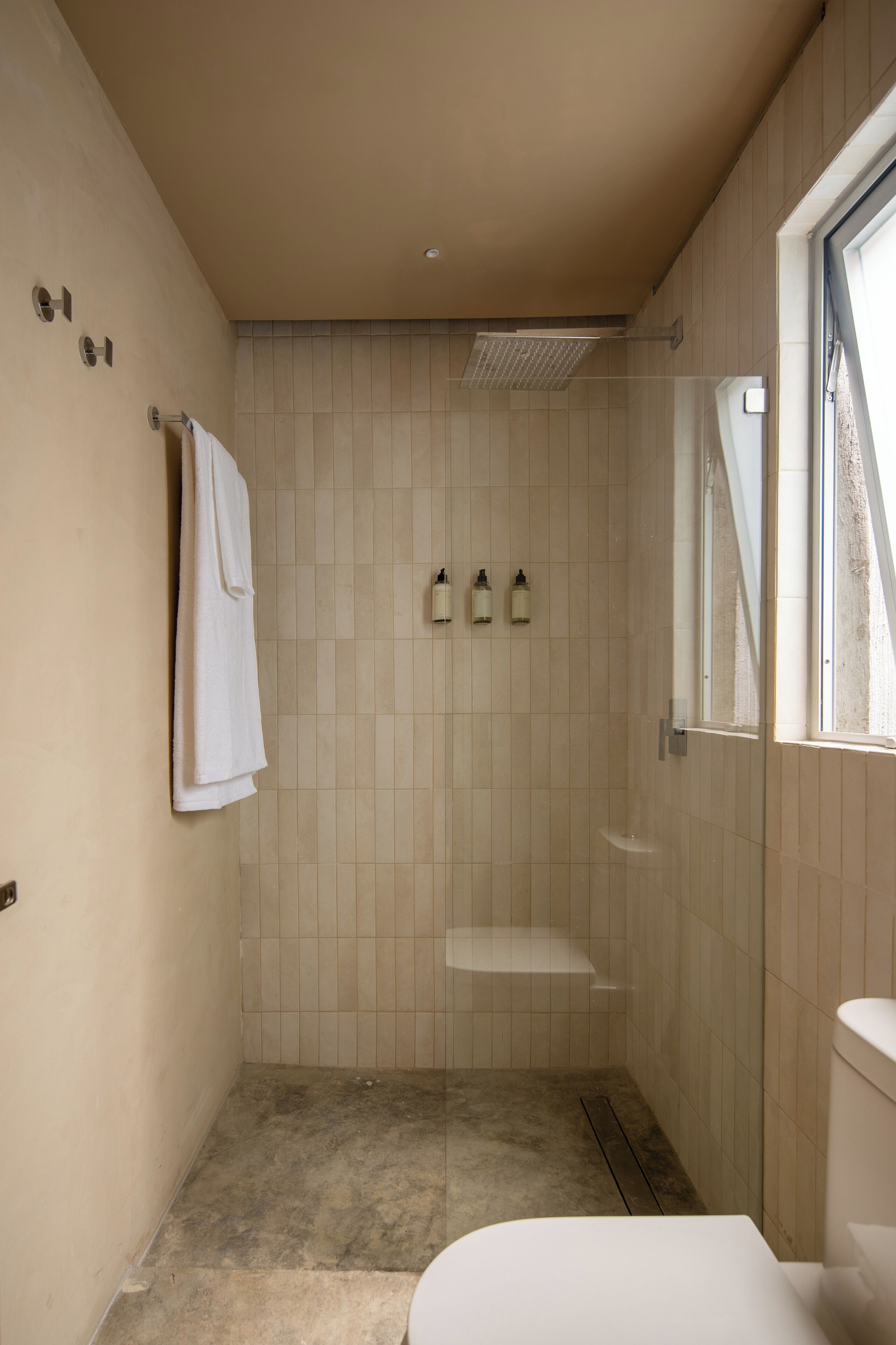 A small, modern bathroom with a shower, toilet, and sink.