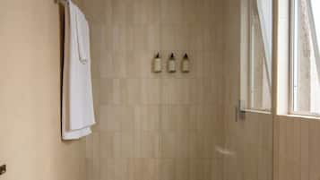Un baño pequeño y moderno con ducha, inodoro y lavamanos.
