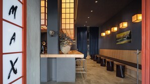 A modern interior with a reception desk, a large vase with flowers, a wooden bench, and a painting on the wall.