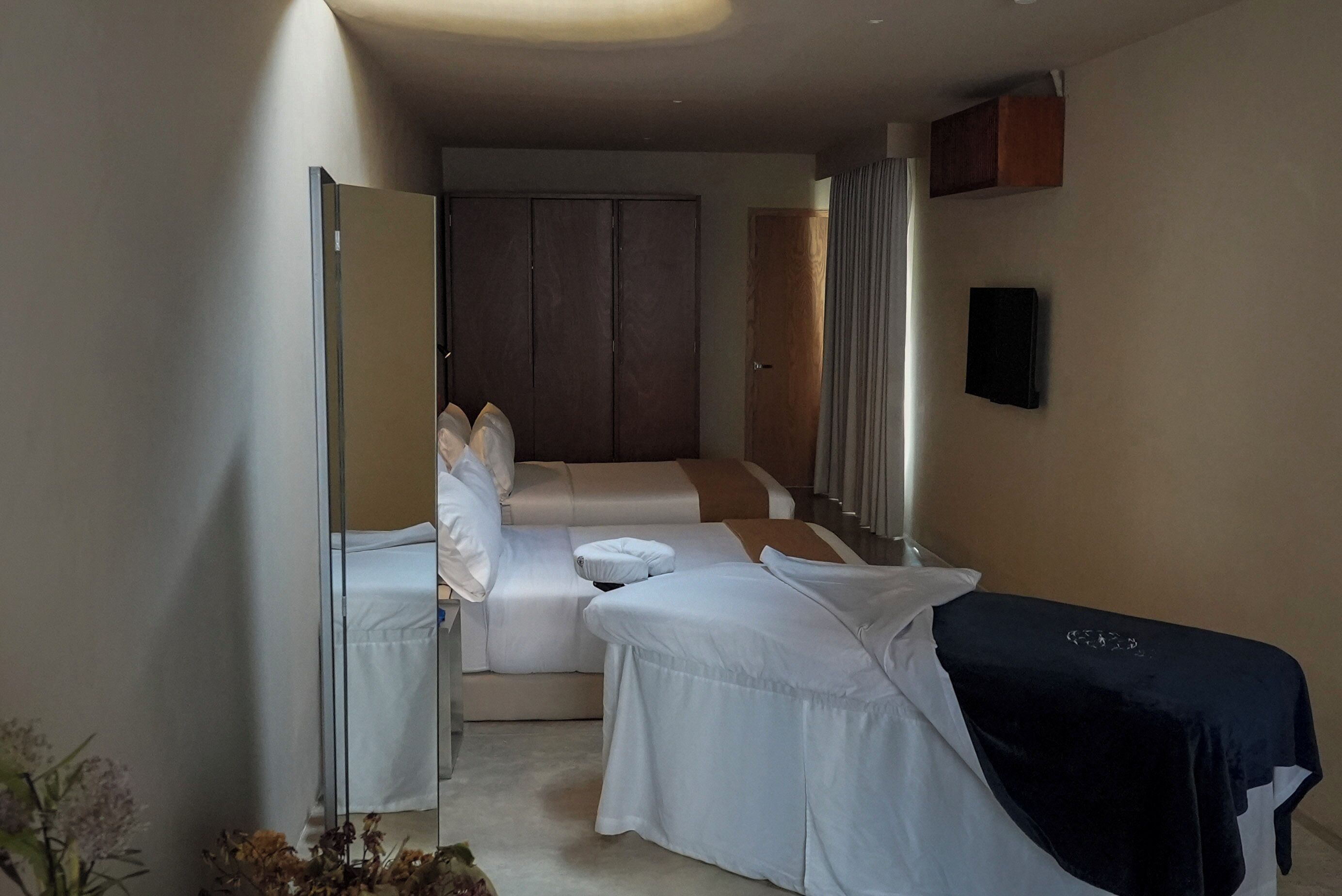 Una habitación de hotel moderna con una cama grande, una zona de estar con sofá, una mesita y un armario.