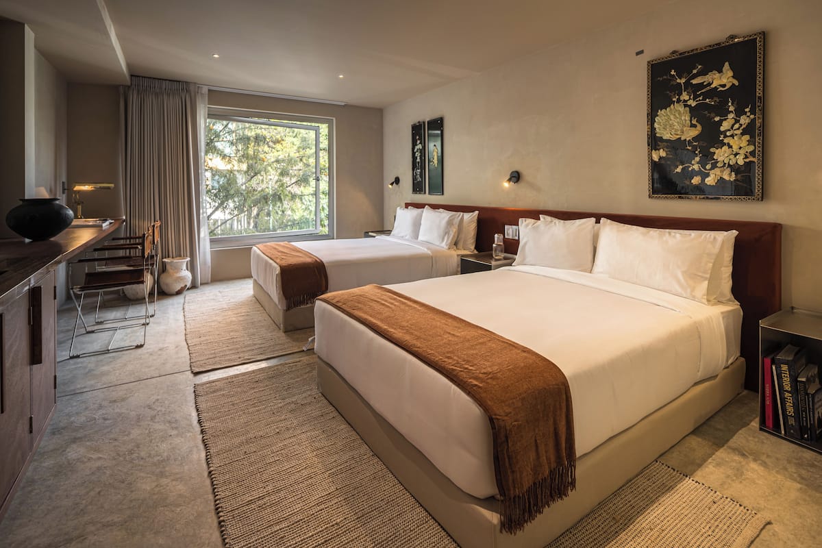 Une chambre d’hôtel avec deux lits, un bureau et une grande fenêtre.