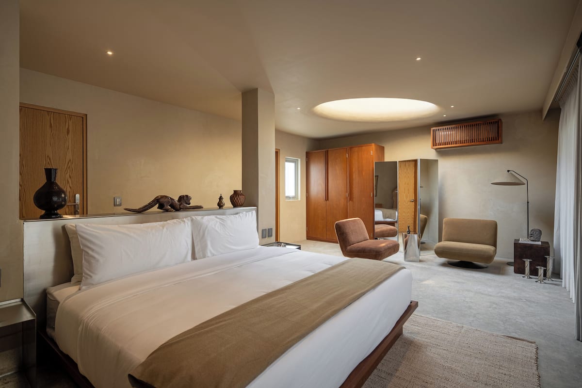 Une chambre à coucher moderne avec un grand lit, une armoire en bois et deux chaises.