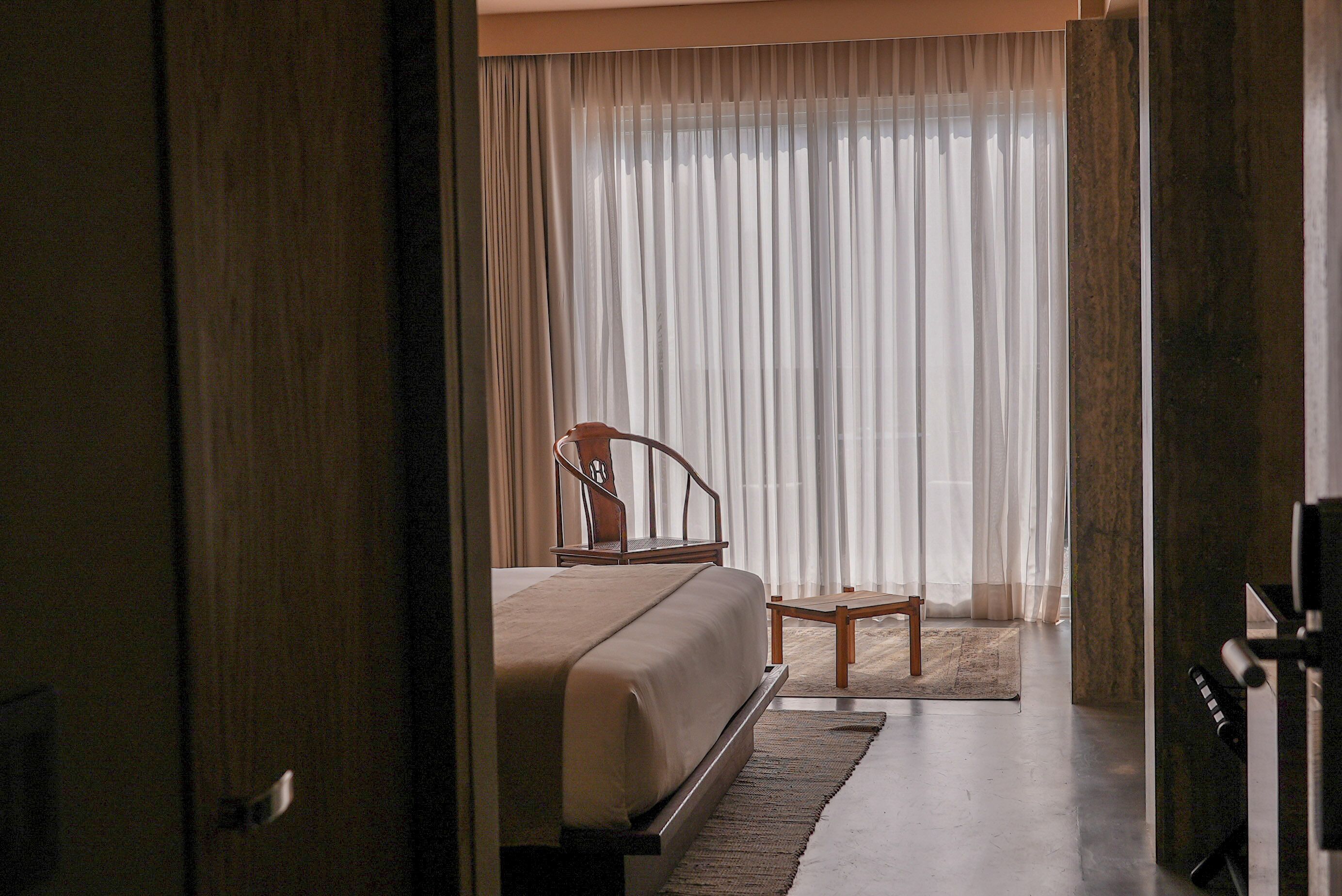 Une chambre à coucher avec un lit, une chaise et une grande fenêtre avec des rideaux.