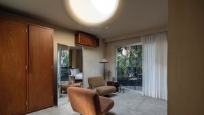A modern bedroom with a large wardrobe, a sofa, and a view of the outdoors through large windows.
